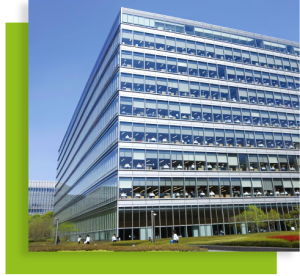 Grand bâtiment tertiaire vitré sur un campus avec chemin piéton et espaces verts