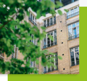 Façade d’un immeuble en briques avec des feuilles d’arbre floues au premier plan