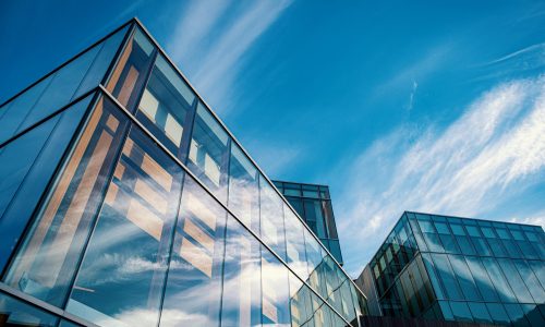Bâtiment moderne en verre reflétant le ciel bleu et les nuages